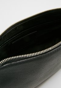 Black textured leather pouch with silver zipper partially open, showing dark fabric interior and small internal pocket.