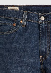 Ceinture de jean en denim bleu foncé avec bouton avant, passants de ceinture, poche avant et détail de couture visible.