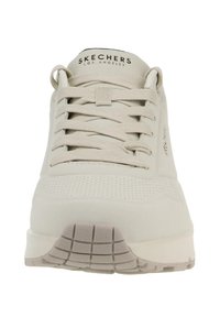 Le sneakers Skechers grigio chiaro presentano una tomaia liscia con dettagli perforati, lacci piatti e una suola in gomma testurizzata con un motivo a griglia.