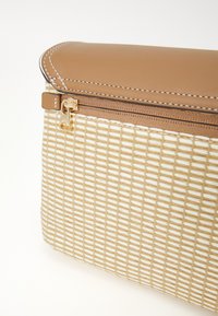 Tan faux leather top, woven beige base with grid pattern, gold zipper closure, and white stitching accents. Compact rectangular shape.