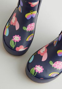 Bottes de pluie marine pour enfants avec un motif de fleurs, papillons, tortues et arcs-en-ciel colorés sur un fond clair.