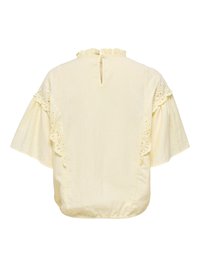 Blouse crème avec manches courtes évasées, bordure en dentelle le long des manches, col à volants et fermeture bouton-passerelle dans le dos au niveau de l'encolure.