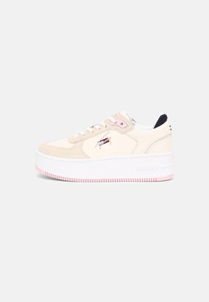 Zapatilla baja beige y rosa con plataforma, cordones blancos y un logo bordado en el lateral, sobre un fondo claro y sencillo.