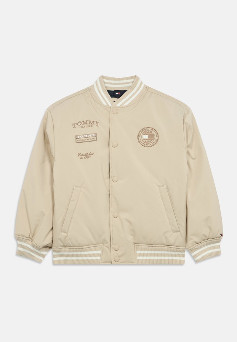 Giubbotto bomber beige con bottoni a pressione, polsini e orlo a coste. Presenta loghi stampati sul petto e sulle maniche, realizzato in tessuto liscio.