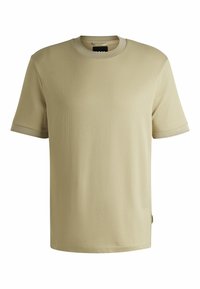 T-shirt beige a maniche corte con texture a coste e colletto a girocollo; presenta un design semplice e una piccola etichetta logo sul lato.