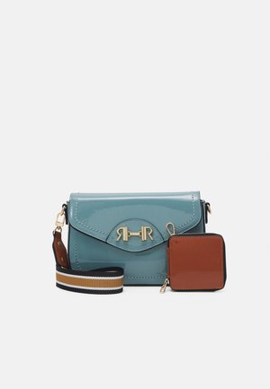 Sac à bandoulière en cuir bleu avec fermeture dorée, pochette carrée marron attachée, et bandoulière rayée noire, blanche et marron réglable.