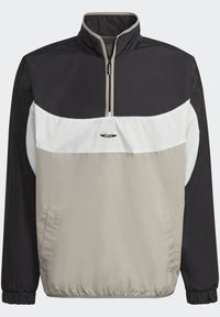 Halvdragkepps vindjacka med svart överdel, vit mittband, beige nederdel, elastiska manschetter och centrerad Adidas-logotyp på bröstet.