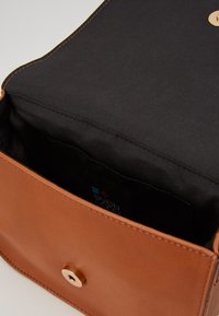 Brązowa skórzana torebka o gładkiej fakturze, wyposażona w czarną podszewkę, złote zapięcie na guzik oraz wewnętrzną kieszeń z metką z logo.