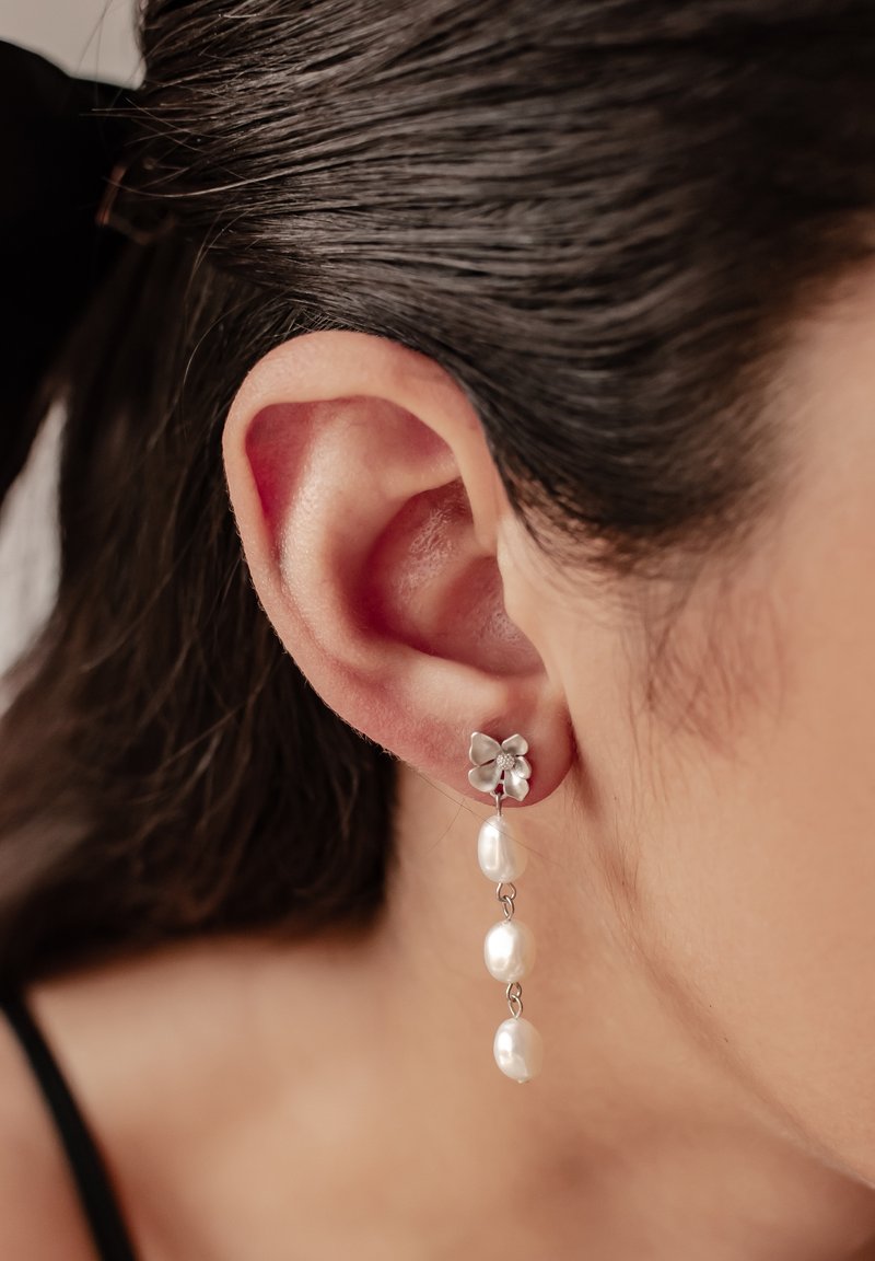 Orecchini a cerchio in argento con tre perle pendenti, dalla texture liscia, con un design semplice ed elegante.