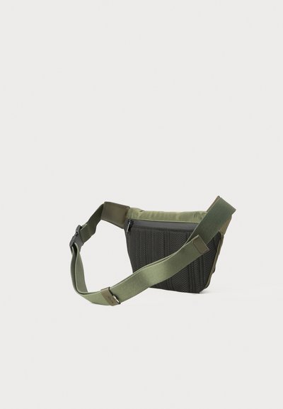 Borsa a tracolla verde oliva con una parte frontale in rete nera testurizzata, cinturini regolabili e chiusura superiore con zip. Design compatto e pratico.