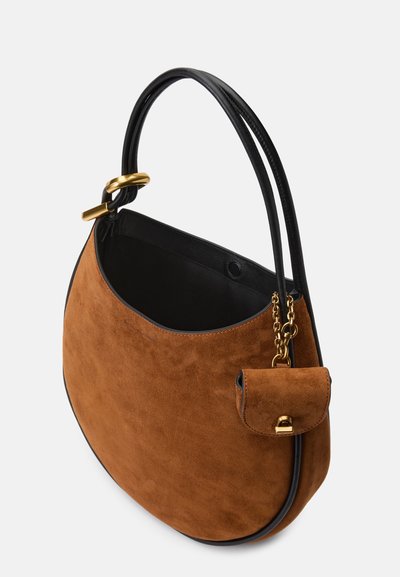 Sac à main en daim marron avec une forme arrondie, accents en cuir noir, une chaîne en or et une petite poche extérieure avec un fermoir.