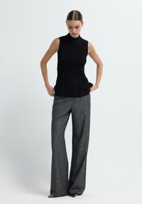 Zwarte mouwloze top met een geribbelde textuur; grijze wijde broek met zilveren spikkels, gladde stof en een losse pasvorm.