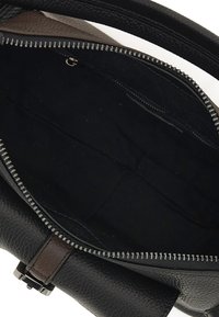 Borsa a tracolla in pelle nera con una superficie texture, zip superiore e un accento in pelle marrone. Interno in tessuto scuro con una tasca con zip.