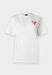 Λευκό βαμβακερό μπλουζάκι με στρογγυλή λαιμόκοψη και κοντά μανίκια. Διαθέτει σχέδιο με ροζ καρδιά που στάζει στην αριστερή πλευρά του στήθους.