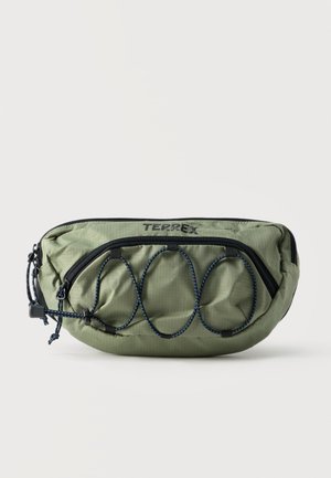 Roheline TERREX vöökott musta tõmblukuga, esiküljel kummipael ja reguleeritav rihm, ühtlase taustaga.