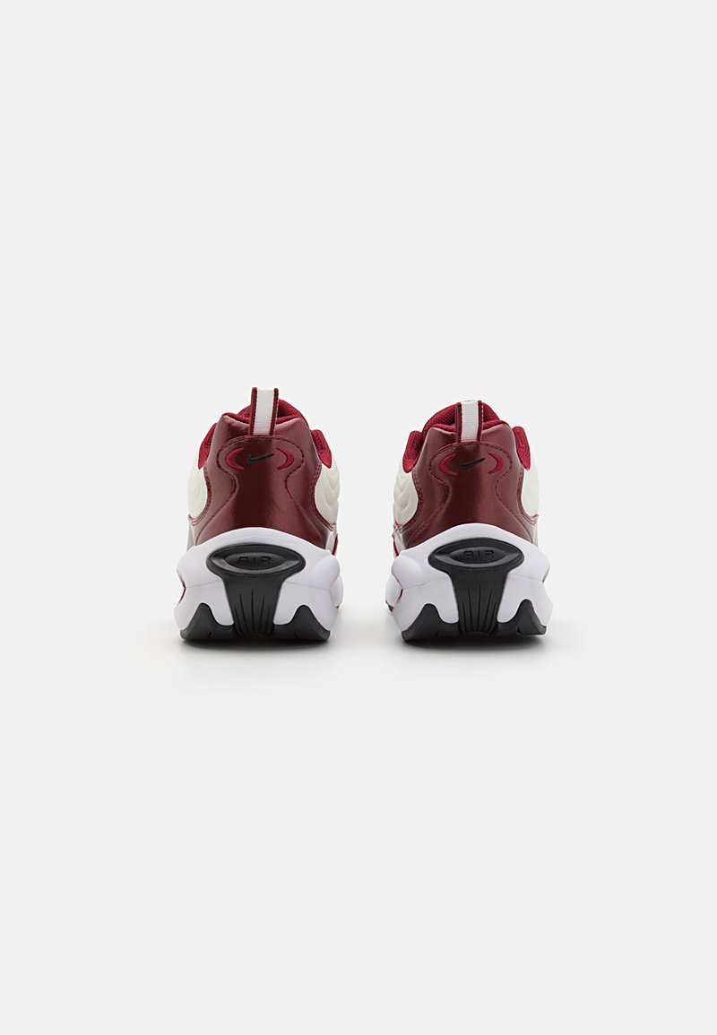 Scarpe sportive rosse e bianche con una tomaia in pelle liscia e mesh, dotate di una suola ammortizzata e suola in gomma; logo Nike sul tallone.
