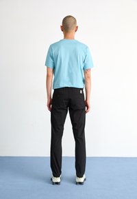 Light blue cotton t-shirt paired with black trousers. The outfit is completed with light shoes. Simple design, casual fit, no visible patterns.