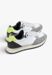 Sporty sneakers with a mix of white leather and grey suede, featuring a bright green accent, black rubber sole, and beige midsole.