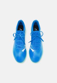 Scarpe sportive blu con tomaia in rete, decorate con un motivo a punti in gradiente, logo bianco e lacci piatti. La suola presenta un dettaglio verde traslucido.