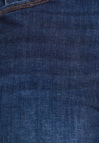 Dark indigo denim fabric with a smooth texture, featuring subtle fading and orange stitching along the seams and pockets.