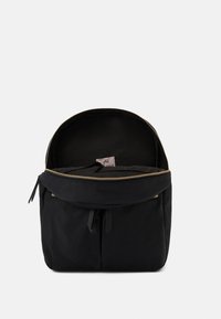 Sac à dos noir en tissu avec une fermeture éclair dorée. Doté d'un dessus arrondi, d'une poche externe et d'un intérieur lisse.
