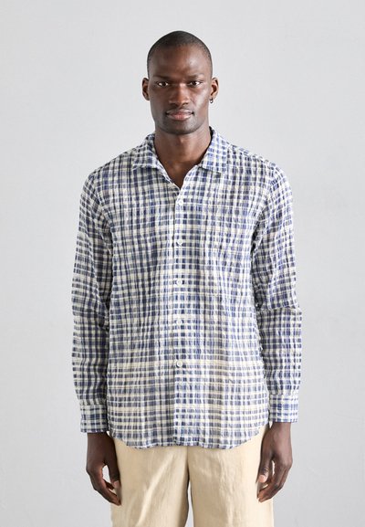 Chemise à manches longues en tissu léger à carreaux bleus et blancs, avec un col et des détails de couture visibles.