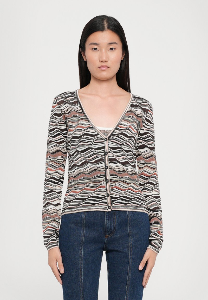 Cardigan a righe con scollo a V, nei colori nero, bianco e con motivi ondulati pastello. Presenta maniche lunghe e bottoni neri lungo la parte frontale.