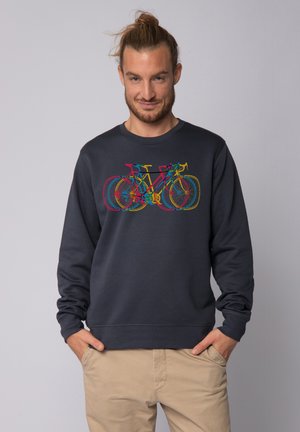 Sweatshirt bleu foncé avec un graphique de bicyclette multicolore. Le tissu semble doux avec des poignets et un ourlet côtelés, renforçant le confort et l'ajustement.