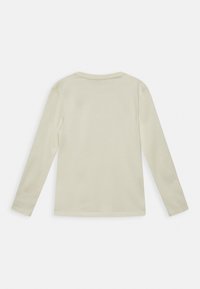 Dlouhý rukáv tričko v světle béžové bavlně. Má kulatý výstřih a jednoduchý design bez viditelných vzorů nebo ozdob.