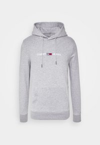 Felpa grigia con cappuccio e tasca a marsupio, dotata di un piccolo logo ricamato "Tommy Jeans" e strisce di colore contrastante sul petto.