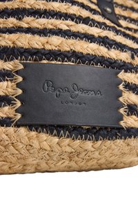 Flätade halmaccessoarer med svarta och naturliga färgsträck; har en svart läderpatch med präglat varumärke och plats.