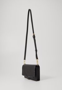 Black leather crossbody bag with a woven edge, magnetic flap closure, and gold-tone hardware. Adjustable strap for versatility.