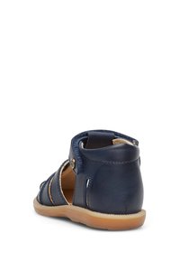 Námořnické kožené sandály s otevřeným designem, nastavitelným popruhem a hnědou podrážkou. Mají výřezy a hladký povrch. Vhodné pro volnočasové nošení.