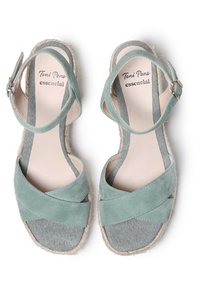 Sandali in suede verde chiaro con design a fasce incrociate, suola in giute stile espadrille e rivestimento in tessuto grigio. Chiusura con fibbia sulla cinghia alla caviglia.