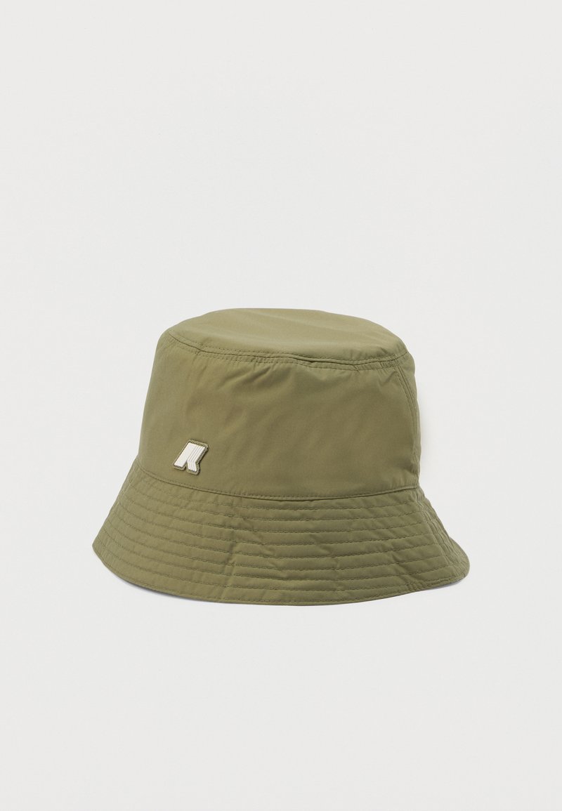 Olijfgroene bucket hat met gestikte rand en klein wit-beige geborduurd logo aan de zijkant tegen een effen witte achtergrond.
