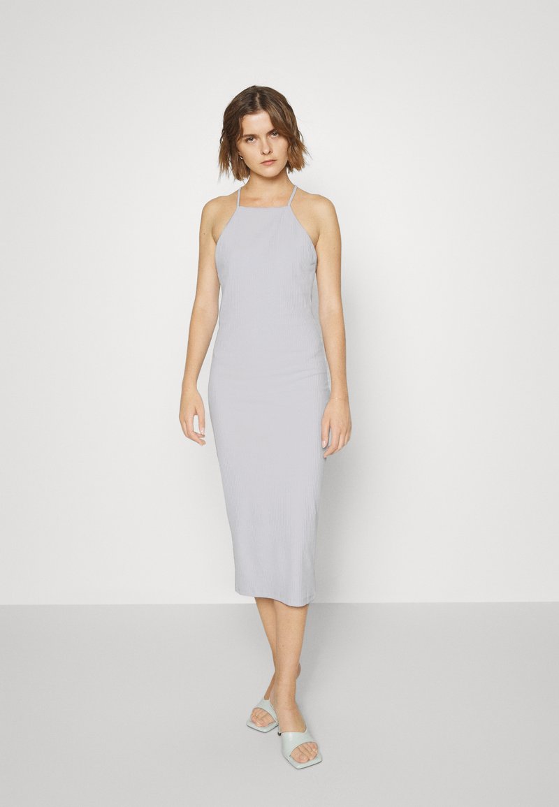 Vestido midi halter em cinza claro com um corte ajustado, combinado com mules abertas em cinza claro com design de bico quadrado.