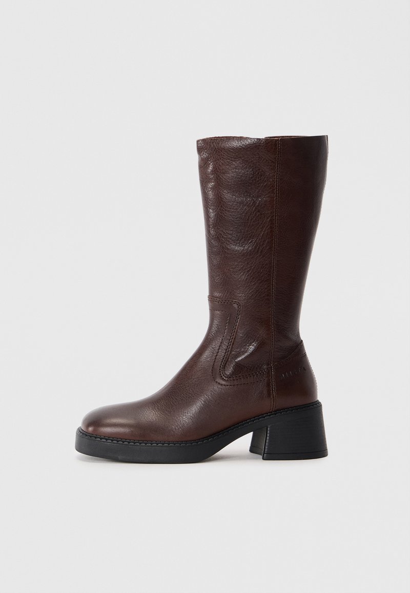 Rjave usnjene čizme do kolen z teksturirano površino, kvadratnim nosom in nizko blok peto. Imajo stranske šive in rahlo razširjen zgornji del.