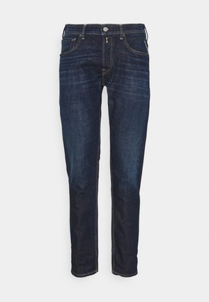Dunkelblaue Slim-Fit-Jeans mit Front- und Gesäßtaschen, Knopf- und Reißverschluss sowie subtiler Verblassung im Oberschenkelbereich.