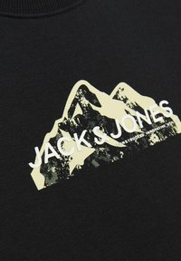 Felpa nera con un design grafico di montagne in giallo e grigio. Include il nome del marchio "JACK & JONES" in bianco.