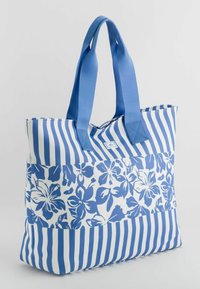 Duża torba na ramię z niebieskimi wzorami kwiatowymi oraz niebieskimi i białymi pionowymi paskami. Wykonana z wytrzymałego materiału z solidnymi uchwytami z tkaniny.