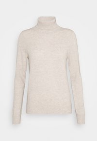 Pull en col roulé beige en tricot doux, avec des manches longues, une coupe ajustée et des accents côtelés autour du col et des poignets.