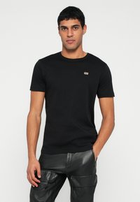 Fekete pamut póló kerek nyakkivágással, a mellkason egy kis téglalap alakú Diesel logóval. Egyszerű dizájn, rövid ujjú.