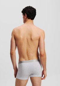 Shorts en coton gris avec une ceinture argentée, vus de l'arrière. Texture lisse et design ajusté.