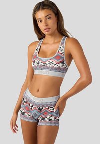 Sportovní podprsenka a šortky v sadě s geometrickým vzorem v červené, šedé a černé barvě, se měkkým elastickým pasem a těsným střihem.