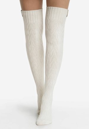 Knielange gerippte Socken in Elfenbein mit einem strukturierten Muster und einem breiten Bündchen an der Oberseite. Mit dekorativen Beschlägen am Bündchen.