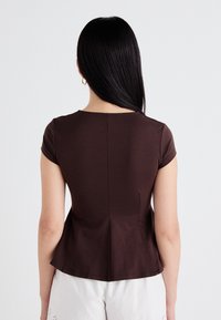 Brown short-sleeve top with a fitted design, featuring a subtle peplum cut and a round neckline. Smooth, stretchy fabric with a solid color.