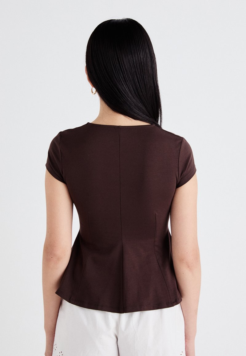 Brown short-sleeve top with a fitted design, featuring a subtle peplum cut and a round neckline. Smooth, stretchy fabric with a solid color.