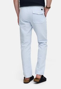 Pantalones de rayas azul claro y blanco con un corte slim, que cuentan con un bolsillo trasero y se combinan con zuecos negros. Acabado de tela texturizada.