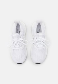 Vita idrottsskor i stickad material, rund tå, snören och märkesseffekter. Texturerad yta och vadderade sulor för komfort.
