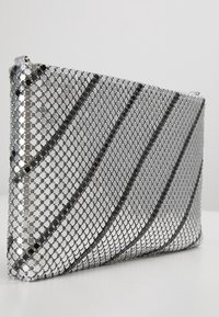 Stříbrná síťová psaníčko s geometrickým vzorem hexagonálních a kruhových flitrů, s hladkým, plochým obdélníkovým designem.